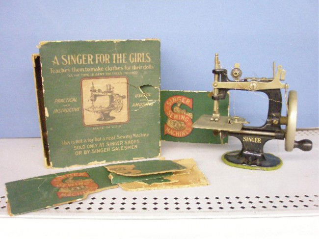 1920's Singer Toy Sewing Machine: 1920's The Singer Manufacturing Company toy sewing machine w/original box. Condition: Very good w/small areas of loss on base, box is torn, felt loss on base.