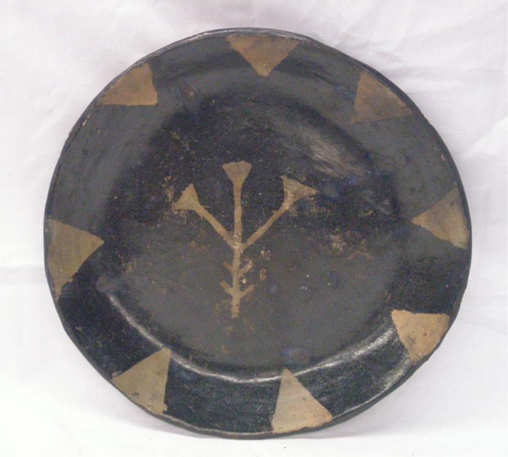 Native American Pottery Plate: Antique Native American pottery 10 3/4" plate, black glazed center with brown arrowhead points along the border & geometric design in center. Condition: Areas with wear & loss.