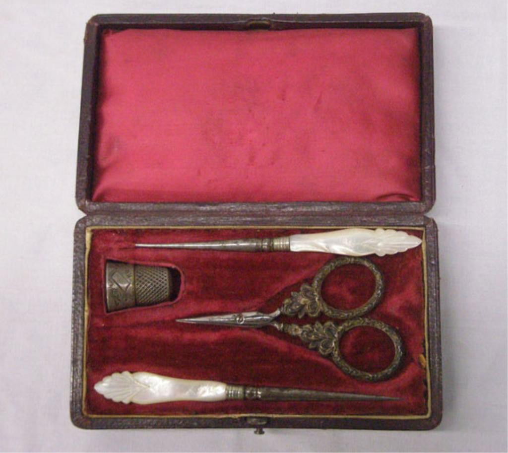 Victorian Traveling Sewing Case: Victorian ladies traveling sewing case with sterling silver thimble, sterling silver handle scissors & two Mother of Pearl handle needle implements. Condition: All pieces have wear & case has wear.