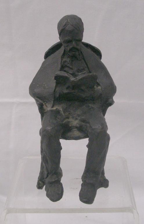 Illegibly Signed Iron Sculpture: Illegibly signed early 20th c. iron 5 3/4" sculpture, depicting an elderly man seated in a Windsor chair, reading a book. Condition: Very good with minor wear.