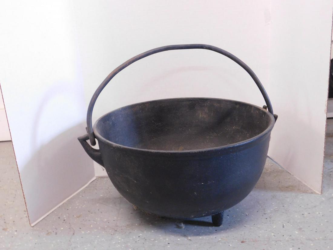 Cast Iron Cauldron: Cast Iron Cauldron, swing handle, three legs, 19"d, 19th / 20th C, very heavy. CONDITION: Areas of rust on interior legs.