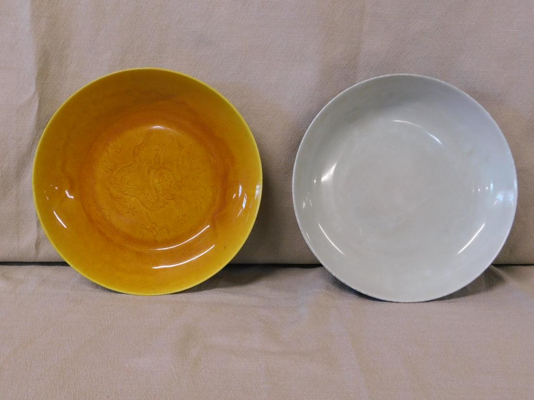 2 Chinese Porcelain Bowls: 2 Chinese Porcelain includes: Amber with under glaze etched dragon, black characters on underside. D 8 11/16", H 1 3/4"; and a black glazed bowl with pale celadon interior, blue underglazed characters