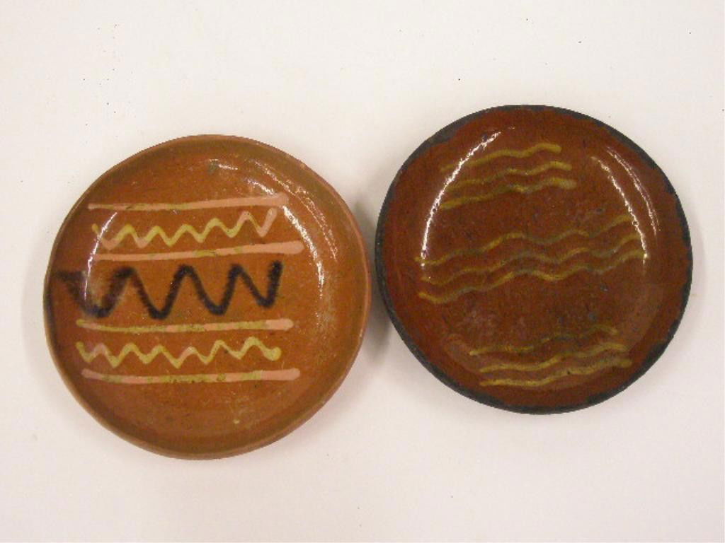 19th c. Redware Slip Decorated Plates: 19th c. Redware 6 3/4" & 7" plates, 6 3/4" with yellow slip wavy line decoration, 7' with yellow & black slip wavy line decoration. CONDITION: 6 3/4" has significant chipping & loss on rim, crazing &