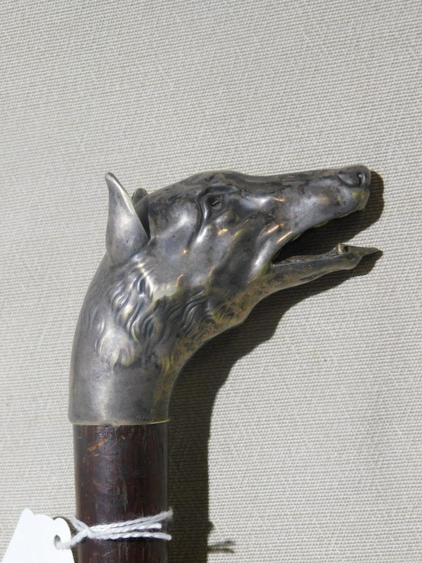 Dog Head Cane: Dog Head Cane. Handle: "Alpaca" silver sculptured dog head with tongue extruding from an open mouth, glass eye. Shaft: Hardwood. Ferrule: brass. Length: 37". Vintage: Early 20th C. [36] CONDITION: Tar
