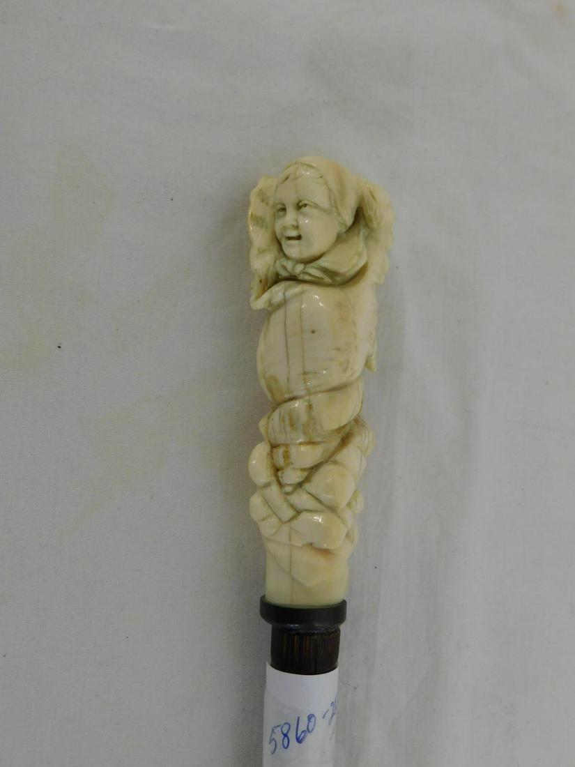 Baby Carved Handle Cane: Baby Carved Handle Cane: Handle: Bone carved baby with bonnet wrapped in a blanket and set in a seashell on rocky formation; 3 3/4"l. Collar: Brass ring. Shaft: Bamboo. Ferrule: Steel and iron. Length