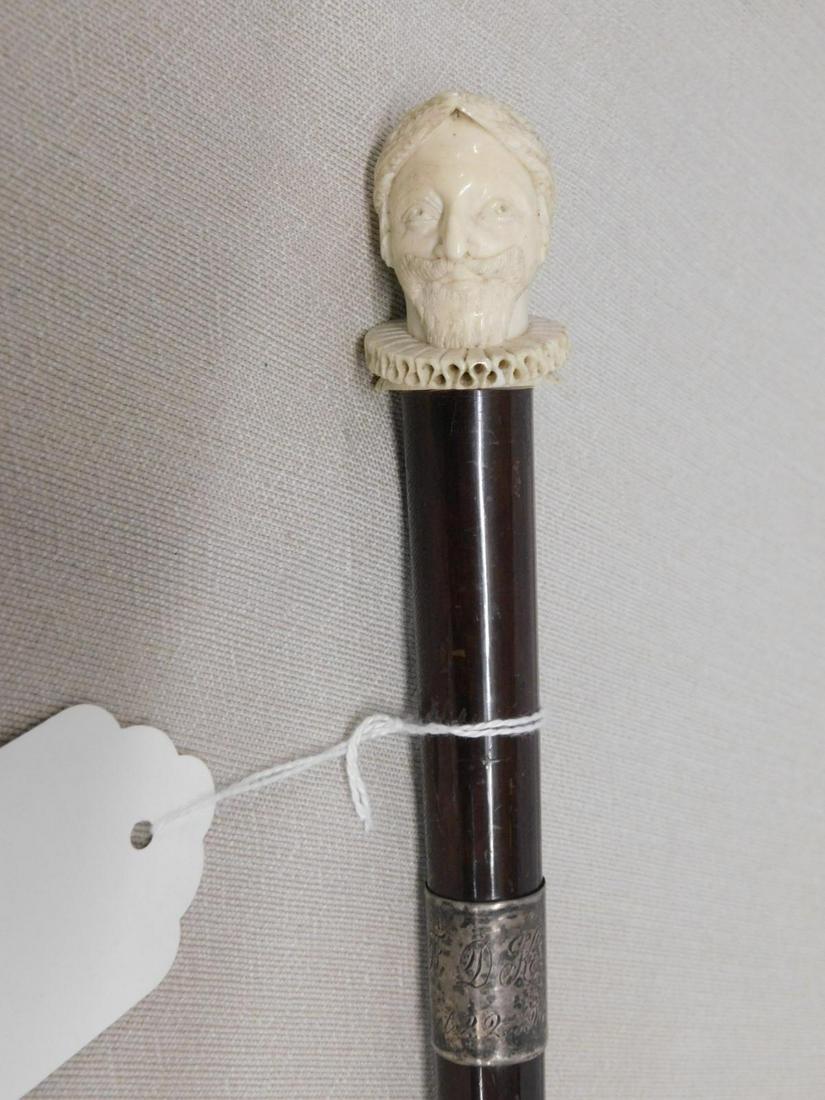Elizabethan Carved Man's Head Cane: Head Carved Cane: Handle: Bone sculptured carved bust of an Elizabethan man with goatee and mustache, wearing a head wreath and crimped collar, 1 5/8"l. Collar: Sterling silver band "DK Oct 20, 1915".
