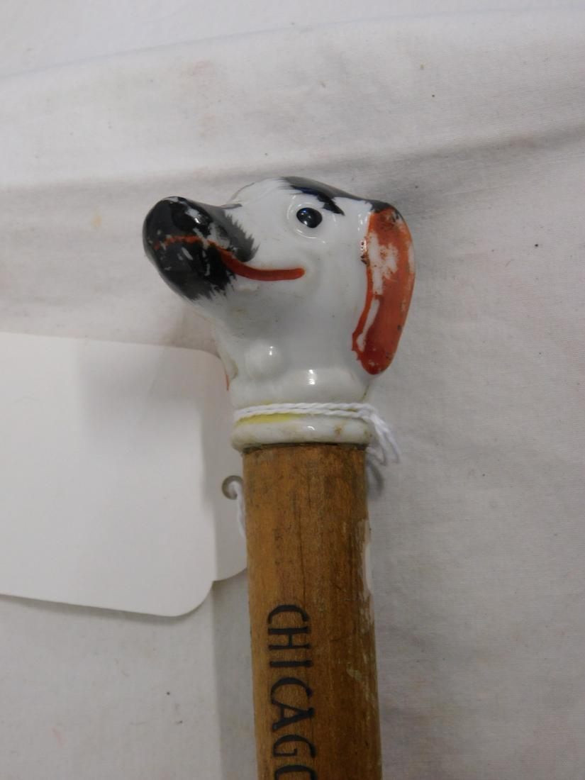 Chicago World's Fair Cane Dog Head: Chicago World's Fair Cane: Handle: Porcelain dog head. Shaft: Hard wood with burnt in "Chicago World's Fair 1933". Ferrule: Silver painted wood. 33" l. [80] CONDITION: Some porcelain paint wear and re