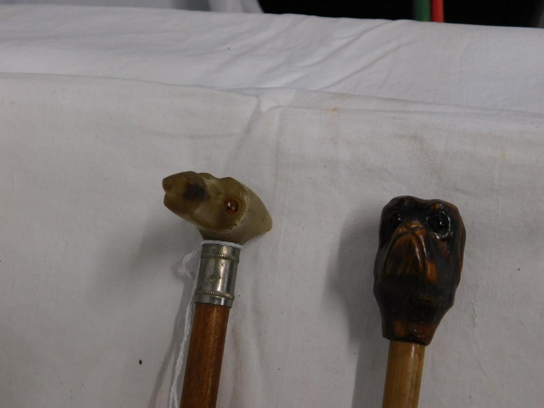 2 Dog Canes: Two Dog Canes, carved wood bull dog head with glass eyes on bamboo shaft, 36"l and a carved horn long nose dog head with glass eyes, metal collar, wood shaft with metal ferrule, 23 1/2"l. [88] CONDITI