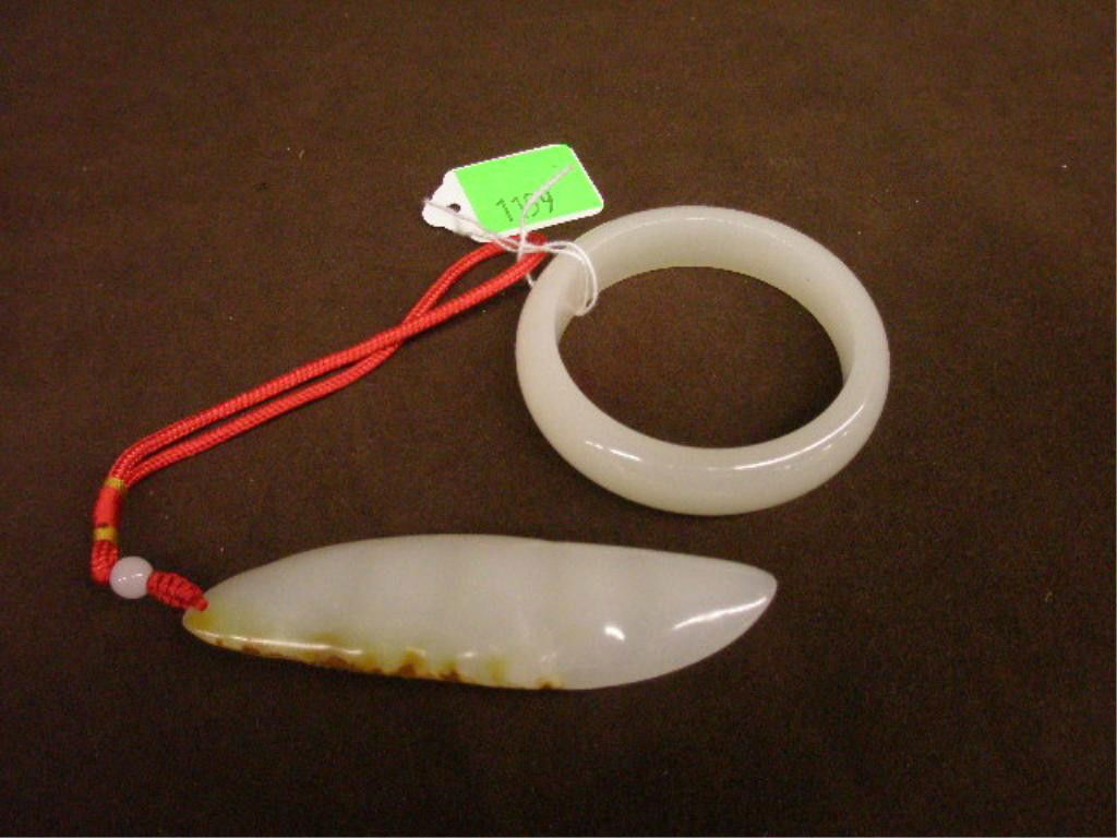 2 Chinese White Jade Pieces: Two Chinese white jade pieces; one carved pea pod pendant 4 1/2", one with caramel accents along one side, attached with white jade bead & red rope strap & one 3 1/4" bangle bracelet, 20th C. [16]