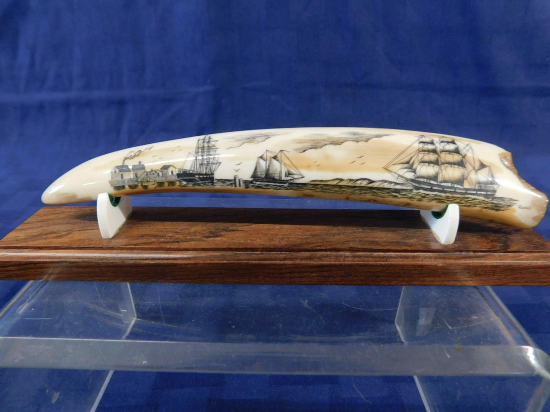 Scrimshaw Tooth: Scrimshaw Tooth, Salman Rashidi signed 7" tooth with New England harbor scene with four boats, factories, mountains and clouds; fitted wood stand, circa 2000.[5] CONDITION: Very fine, natural tooth im