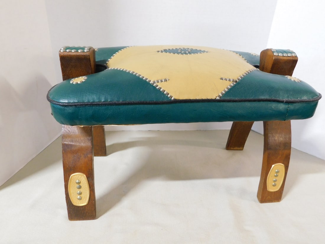 Moroccan Camel Saddle: Moroccan Camel Saddle, hardwood frame with stitched green and yellow leather upholstery, oval brass leg mounts with tacking, mid 20th C, 20" x 12 1/2" x 11". CONDITION: A few wood rubs, open joint in 