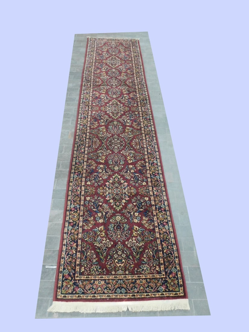 Sarouk Style Runner: Sarouk Style Runner, Karastan (labe3led), maroon ground with overall blues, beiges, black and greens floral field and borders, mid 20th C, 2.6" x 12'. CONDITION: Very light use.