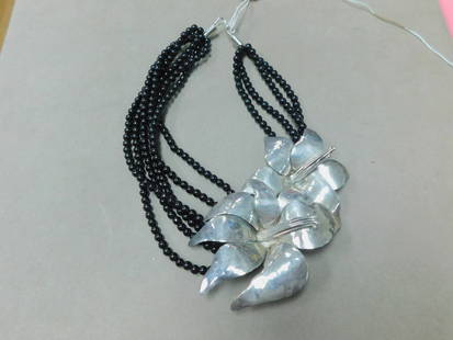 Sterling & Onyx Necklace: Sterling & Onyx Necklace illegible artist signed sterling silver twin flower sculpture (5 1/2" x 3") is joined by multi strands of black onyx beads, L 17 1/2". CONDITION: Used