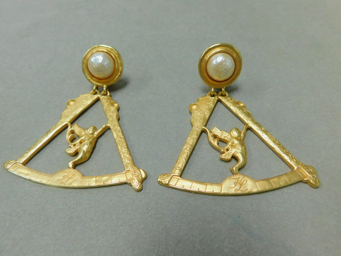 Pr Karl Lagerfeld Scale Cherub Earrings: Pair Karl Lagerfeld Scale Cherub Earrings, gold plated, faux pearls, signed KL, 3 1/4"l. 2 1/2" width, clip on. Features Masonry scale and cherub. CONDITION: Preowned, very good.