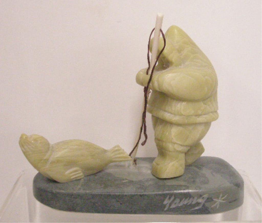 Norman Young Inuit Stone Carving: Norman Young signed 5 1/4" x 6" Inuit stone carving of man with bone staff & seal. CONDITION: Very good with minor wear.