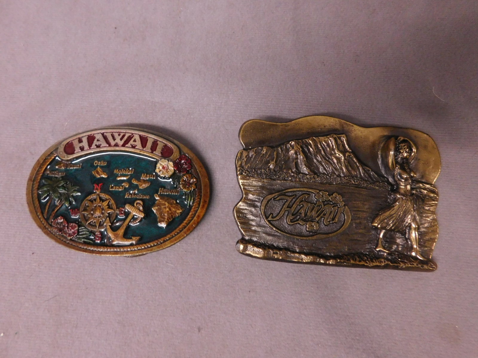 2 Vintage Hawaii Souvenir Belt Buckles: Two Vintage Hawaii Souvenir Belt Buckles, including: enamel JOPA Distributing, © 1985, red and blue enamel with raised relief islands, nautical items, flowers and trees, oval, 2 1/4' x 3", plus brass
