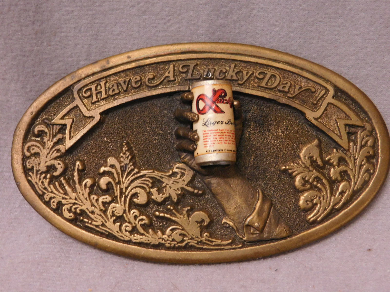 Rare Vintage Lucky Lager Beer Buckle: Rare Vintage Lucky Lager Beer Buckle brass belt buckle with 3-D hand holding aluminum Lucky Lager beer can, Adezy Ent. Inc, 1977 "Have a Lucky Day!", 2 1/4" s 4". CONDITION: Very good.