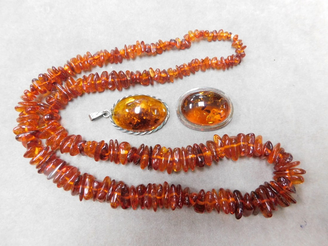 Amber Necklace, Pin & Pendant: Amber Necklace, Pin and pendant, includes: 25" graduated nugget form necklace, a sterling silver framed oval cabochon 1 1/4"l pin and a sterling rope framed oval 1 1/4"l drop. CONDITION: Very fine. Pr