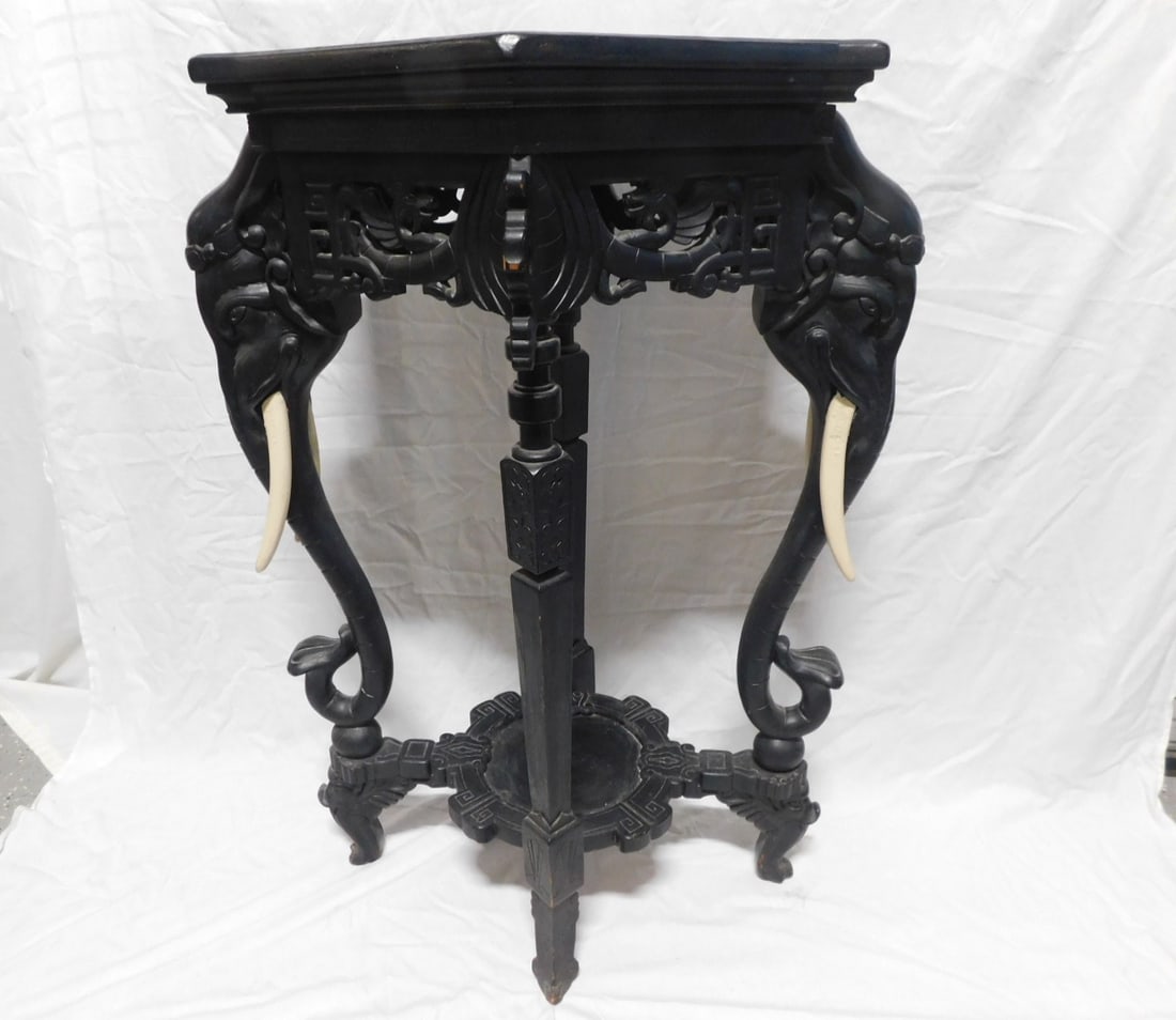 Chinese Elephant Stand: Chinese Elephant Stand, ebonized wood, shaped top over a through carved and unused frieze dragons and scrolls, two elephant head, carved legs, over a base shelf and shaped feet, 19th / 20th C, 24" x 1