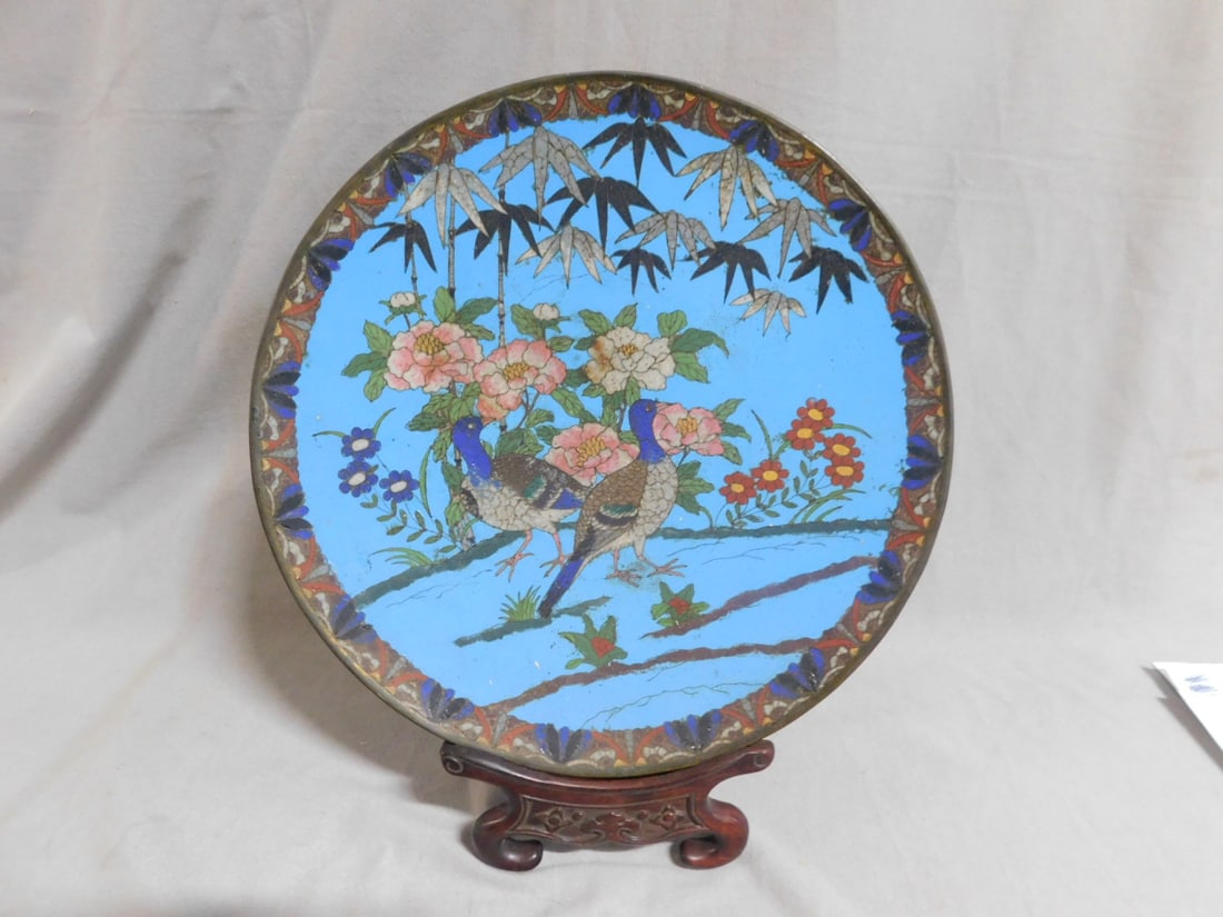 Chinese Cloisonne Charger: Chinese Cloisonne Charger, 12" d, pale blue ground with two birds in floral garden setting, fan and scroll border, late 19th C, includes: carved rosewood stand. CONDITION: Light pitting and wear; craz