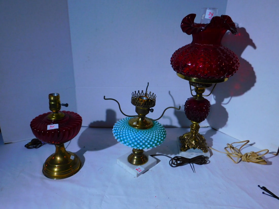 3 Colored glass lamps: 3 Colored glass lamps, green opalescent hob nail, ruby molded glass font and ruby hob nail glass lamp and shade, 21" h. Condition: very good, brass tarnish and brass split at bottom of opalescent lamp
