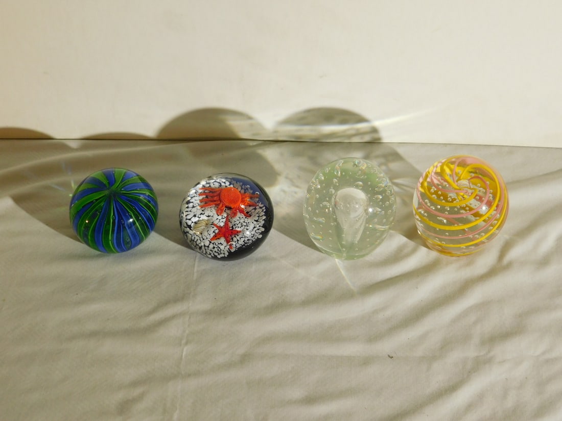 4 Glass Paperweights: Four Glass Paperweights, includes: crab and starfish; blue / green Latticino oval clear bubble glass, surface shatter marks, and an oval spiral and bubble glass, 20th C. CONDITION: Very good.