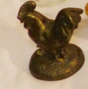 Rooster Bottle Opener: Rooster Bottle Opener, bronze patinated spelter metal, fully sculptured rooster on a grass molded with base with bottle opener beneath, early 20th C, 4" x 3 1/4" x 2 1/4". CONDITION: Very good.