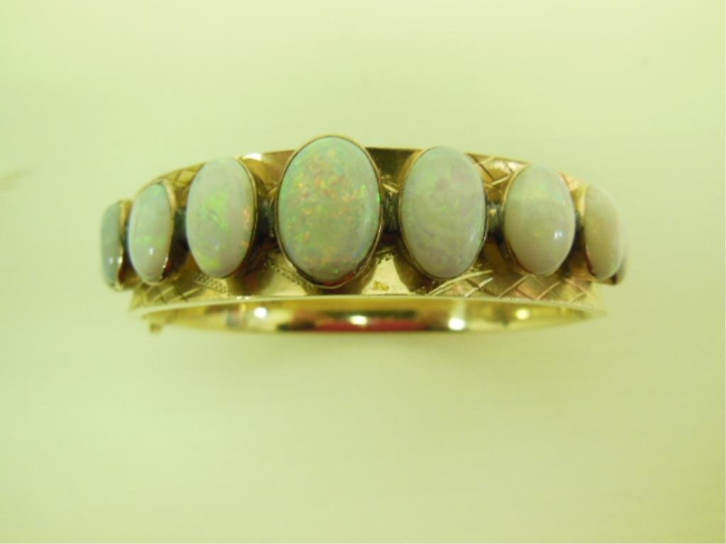 14k Gold & Opal Hinged Bangle Bracelet: Gold and opal hinged bangle bracelet, 14k yellow gold with florentine and etched lattice and diamond designs, crested by nine fiery oval cabochon opals from 6 x 8mm to 9 x 12mm, 17.4 DWT. CONDITION: I