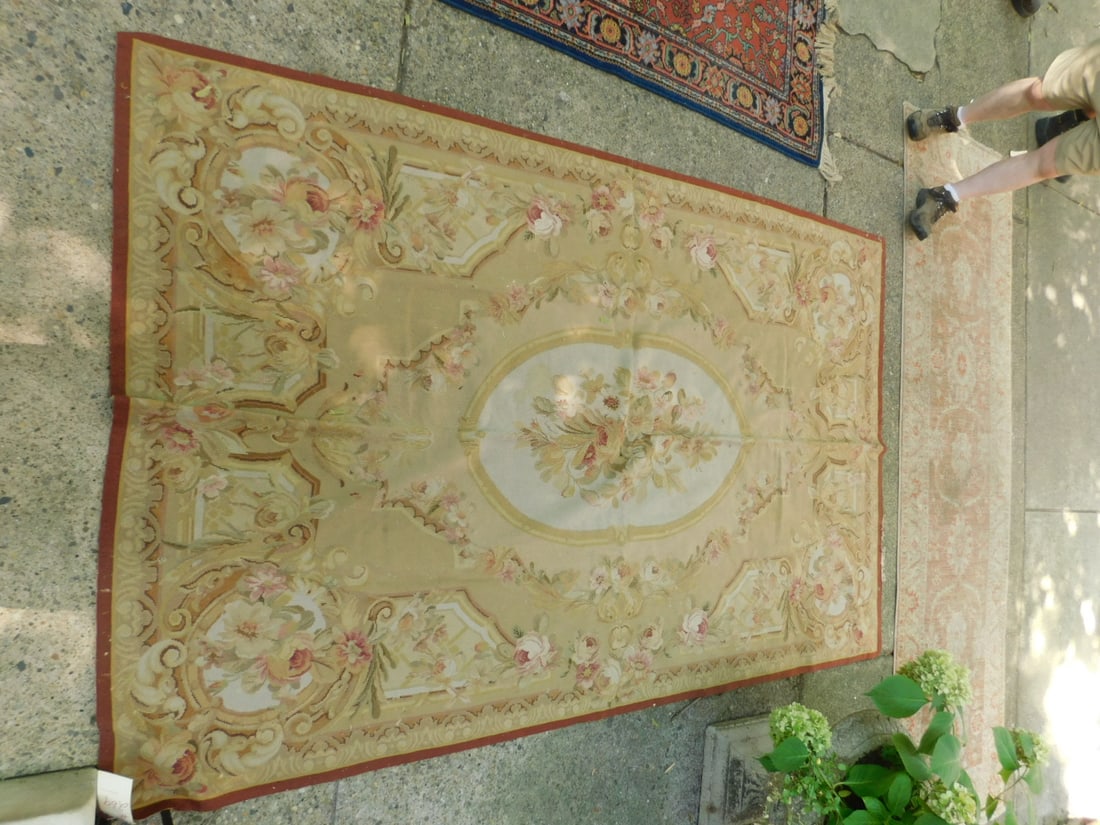 Aubusson Carpet: Aubusson Carpet hand woven, beige ground with yellows and reds floral medallion and borders, early to mid 20th C, 95" x 59". CONDITION: Folds, small moth hole spots.