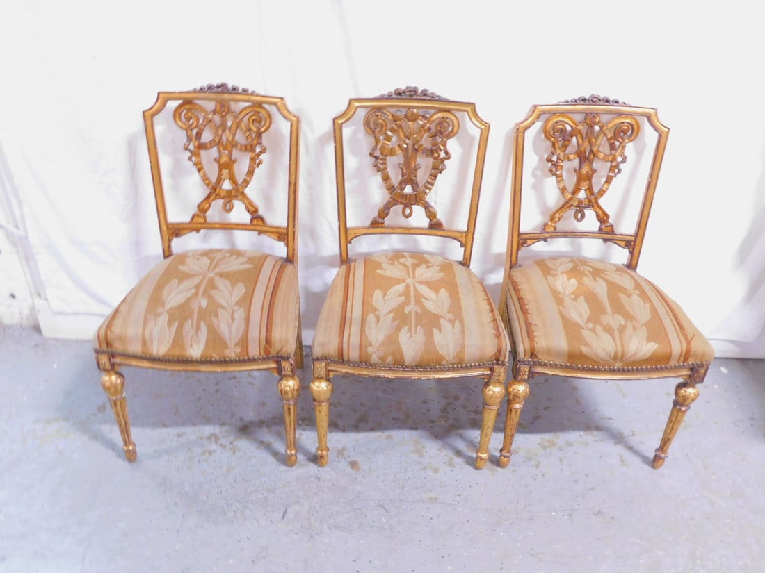 Set 3 Louis XVI Chairs: Set three Louis XVI Chairs, gilt wood, rose carved crest rail, ribbon, bow and scroll carved backs, upholstered seats, 34"h, 19th C / 20th C. CONDITION: Areas of gilt wear.
