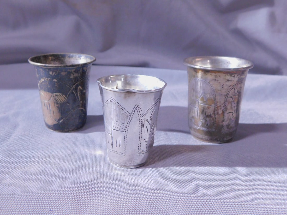 3 Russian Kiddush Cups: Three Russian Kiddush Cups, 84 silver purity and other touch marks, each with scenic and foliate etchings, late 19th C, includes: 1 7/8", 1 3/4" and 1 5/8", 1.85 ozts TW. [104] CONDITION: Tarnished, a