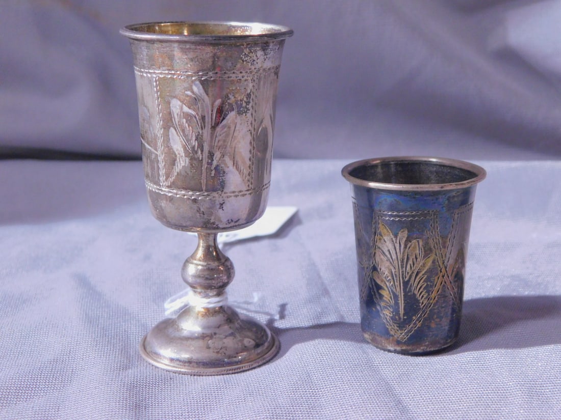 2 European Kiddush Cups: Two European Kiddush Cups, silver and maker touch marks, each with scenic and foliate etchings, includes: 3" goblet and 1 5/8" cup, late 19th c, 1.15 ozts TW.[105] CONDITION: Very good, tarnished.