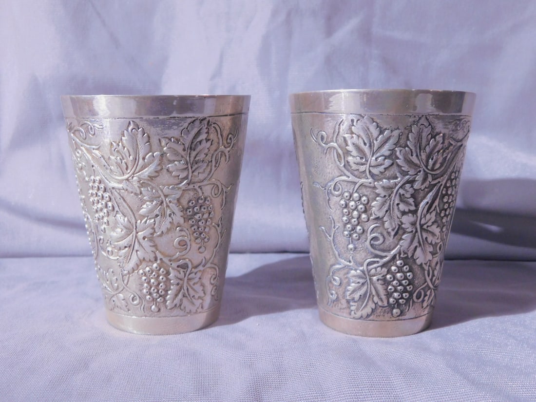 Pr Silver Kiddush Cups: Pair Silver Kiddush Cups, marked 800 silver grape cluster and scroll overall repousse and chaised with beaded border cartouche, early 20th C, 3 3/8"h, 7.65 ozts TW.[144] CONDITION: Very fine.