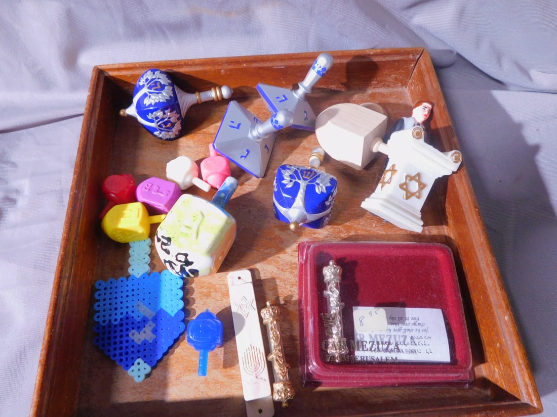 Dreidels & Mezuzah Group: Dreidels and Mezuzah Group, includes: thirteen wood, ceramic and plastic Dreidels, two car Mezuzah (one in original box); one plastic Mezuzah and Bar Mitzvah plastic cake topper. [96] CONDITION: Mostl