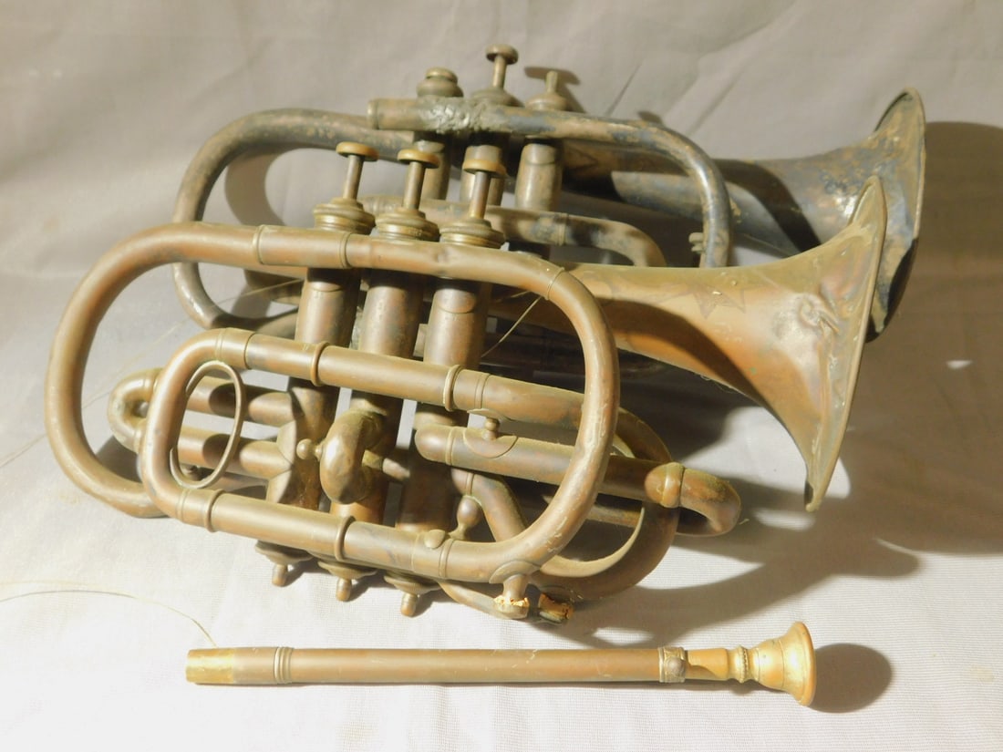 2 Antique Cornets: Two Antique Cornets, brass, includes: Carl Fischer,and Eugene La Leuei - Paris, late19th C, one with mouth piece. CONDITION: Both as is tarnished, dents and bends, old soldier repairs, missing one mou