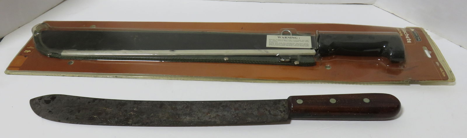 2 Machetes: 2 Machetes including: one new in package - Ozark Trail, 18" with blade guard and canvas sheath, plus one vintage Dexter 11914 (marked on wood handle), 14" carbon steel blade, 19 1/4" overall length. C