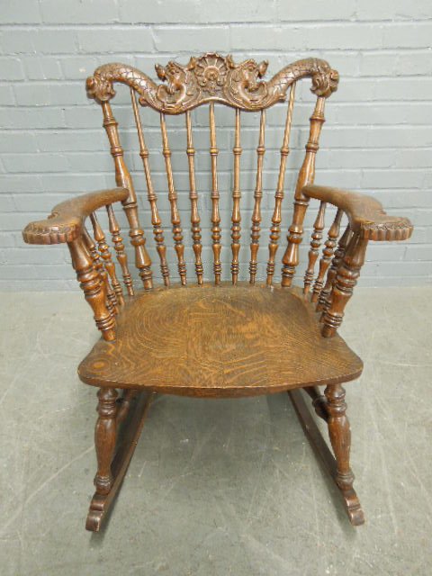 Stickley Rocker: Stickley Rocker, oak, dragon & shell carved crest over spindle back & seat; partial paper label on underside, early 20th c. 32" x 25 1/2" x 31". CONDITION: No issues identified.