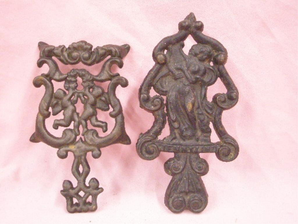 Antique Cast Iron Trivets: Two antique painted cast iron trivets, 2" x 4 1/2" x 9" Jenny Lind & 1" x 4 3/4" x 3 3/4" with cherubs & flowers. CONDITION: Both have wear from usage, no damage.