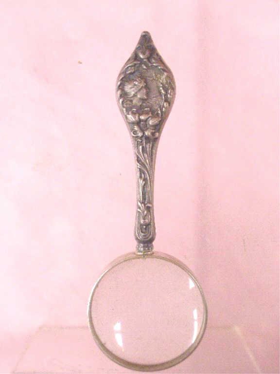 Sterling Silver Handled Magnifying Glass: Late 19th c. Theodore W. Foster & Bro. Co. sterling silver handled 4 1/2" magnifying glass, Art Nouveau female head and floral design on handle. CONDITION: Wear from usage and age.