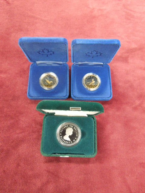 3 Canadian Coins: Three Canadian coins includes: (1) 1984 "Jacques Cartier" dollar and (2) 1987 "Loon Dollars", all in clear plastic coin case with fitted box. CONDITION: No issues identified.