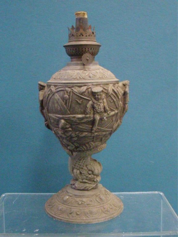 19th c. Nautical Themed Oil Lamp: 19th c. cast metal 12" nautical themed oil lamp, depicts relief sailors working on their ship, dolphin form stem, relief floral & shell form borders, original brass fittings. CONDITION: Overall wear f