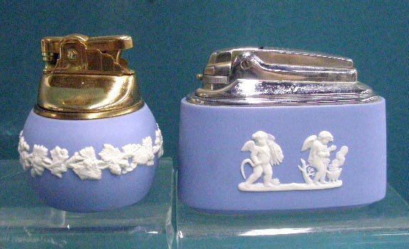 Wedgwood Jasperware Lighters: Two Wedgwood blue Jasperware table top lighters, 2 1/2" round with floral designs & 3 1/2" oval with cherub designs. CONDITION: Both are non-working with no damage.