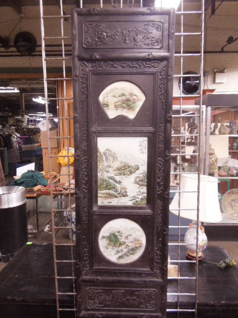 Chinese Porcelain & Wood Triptych Panel: Chinese porcelain & wood triptych panel, panels depict panoramic landscapes; The ebony? relief carved frame features still life, scrolls, bats, 19th/20th C., 15" x 49". CONDITION: No issues noted.