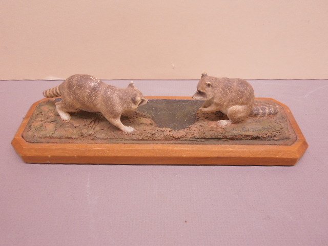 Louis F. Jonas Studios Sculpture: Louis F. Jonas Studios Sculpture, two raccoons, polychromed over composition?, fitted wood base, signed and dated "./77", 10 1/2" x 3' x 3". CONDITION: Small rubbed areas of polychromed loss.