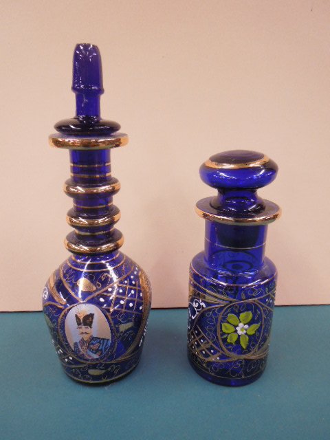 (2) Russian Cobalt Glass Cologne Bottles: (2) Russian Cobalt glass Cologne bottles, with gilt & painted highlights, one with print overlay of a Russian Soldier; late 20th C., hgt 8" & 11". CONDITION: Small scratch on edge of Soldier print.