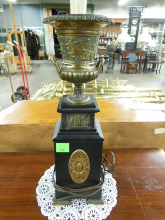 French Empire Style Table Lamp: French Empire style table lamp, bronze Roman style urn rests upon an ebonized wood plinth having an inset relief cast bronze scenic panel above a gilt wood rosette, early to mid 20th C.