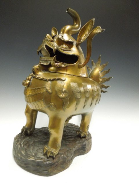 Chinese Bronze Foo Dog Incense Burner: Chinese bronze foo dog incense burner, large scale, features a hinged head crested with a chimney trunk; cast applied & engraved features, fitted wood base; 19th c. 11" x 15 3/4" x 7 1/2". CONDITION: 