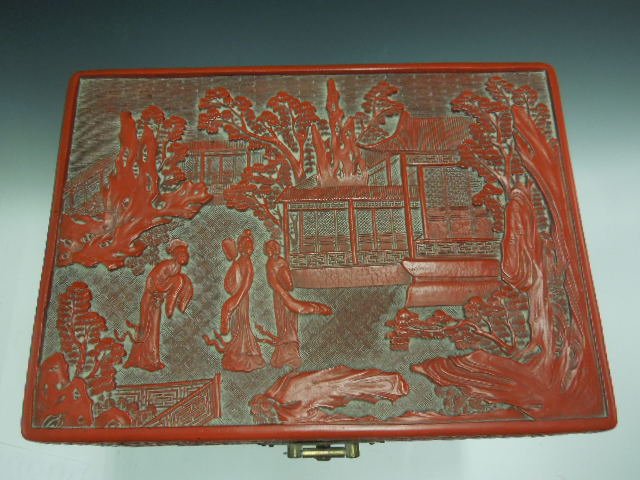 Chinese Cinnabar Jewel Box: Chinese cinnabar jewel box, lift lid with high relief court scene, sides with scroll & floral relief, brass front escutcheon, signed on base; mirror & black velvet fitted interior, mid 20th c. 11" x 8