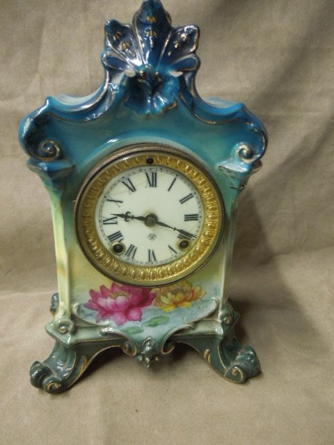 Bonn-Germany Mantel Clock: Bonn-Germany Mantel Clock, Blue ground with floral transfer & paint; Ansonia time & strike movement; early 20th c. 8 1/2" x 11" x 5". CONDITION: Two feet have been glued together; two small scrolls br