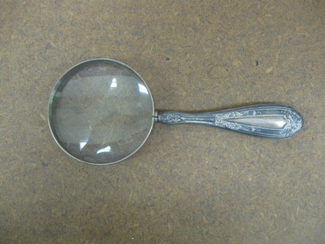 Sterling Handle Magnifying Glass: Sterling handle magnifying glass sterling hallow handle with floral & fan design, lens frame marked Japan, 20th c. length 6 1/4", diameter 2 1/2". CONDITION: Tarnished.